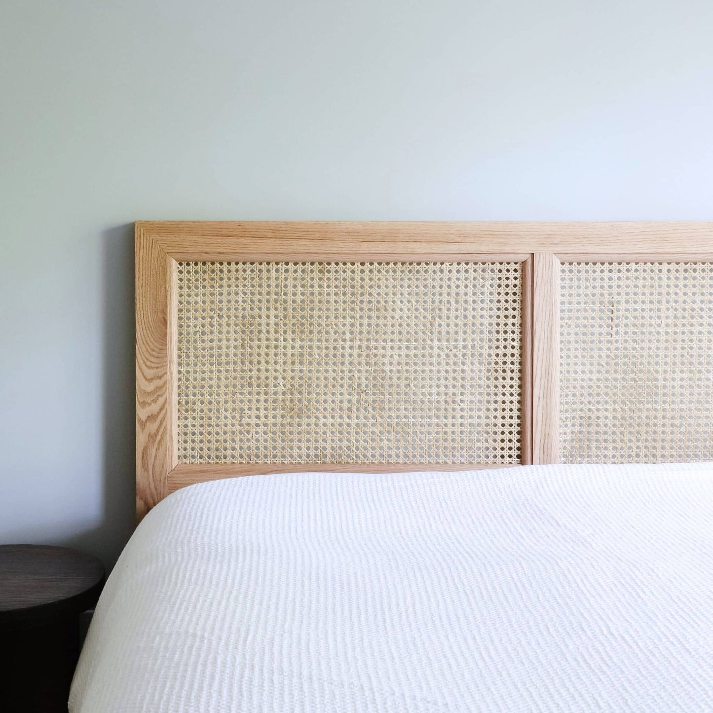 Cane Headboard attached to a bed with white sheets