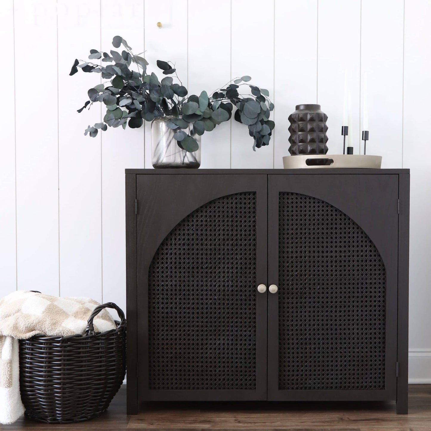 front view of DIY accent cabinet with cane doors in front of shiplap wall with decor on top