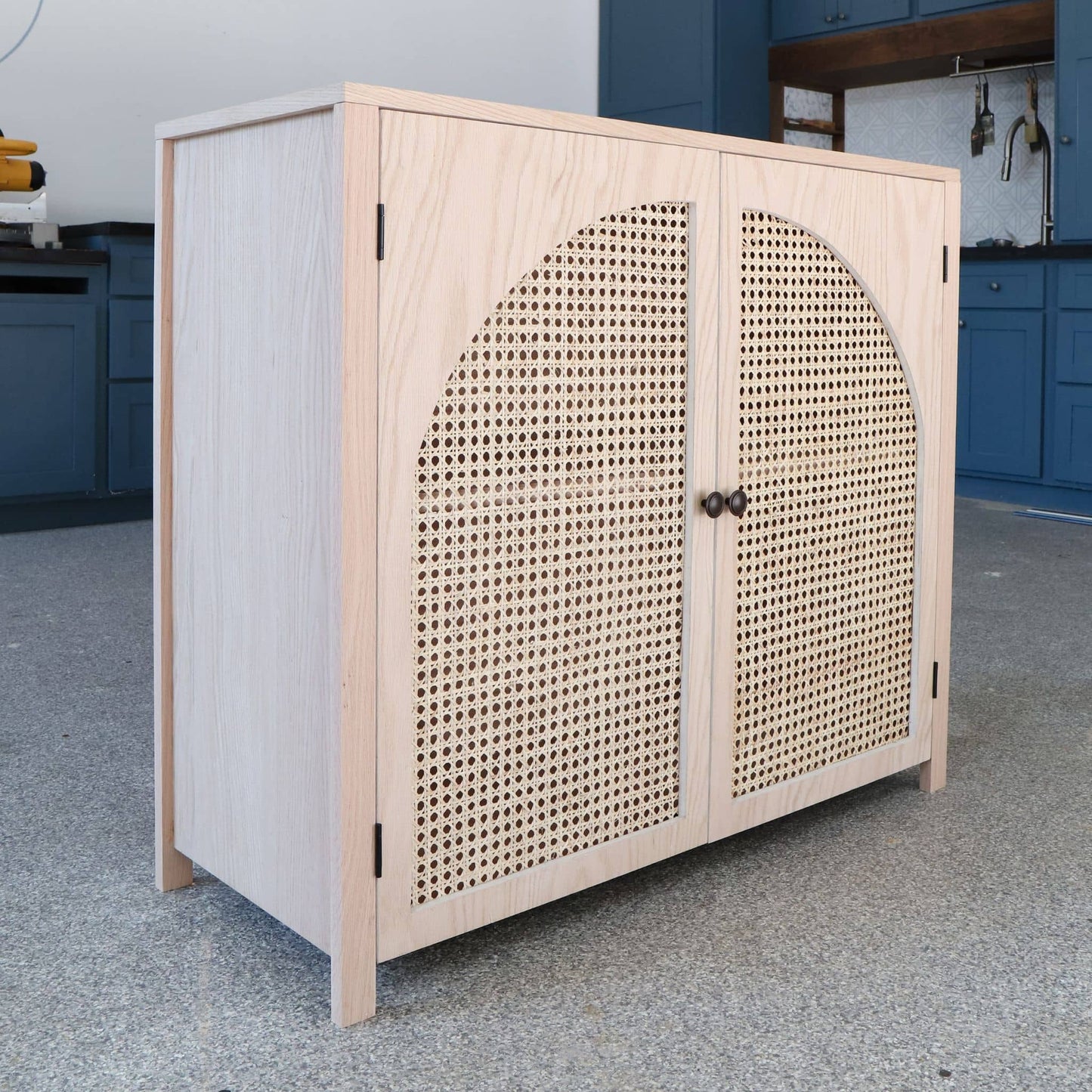 Side angled view of DIY accent cabinet with cane doors in red oak plywood
