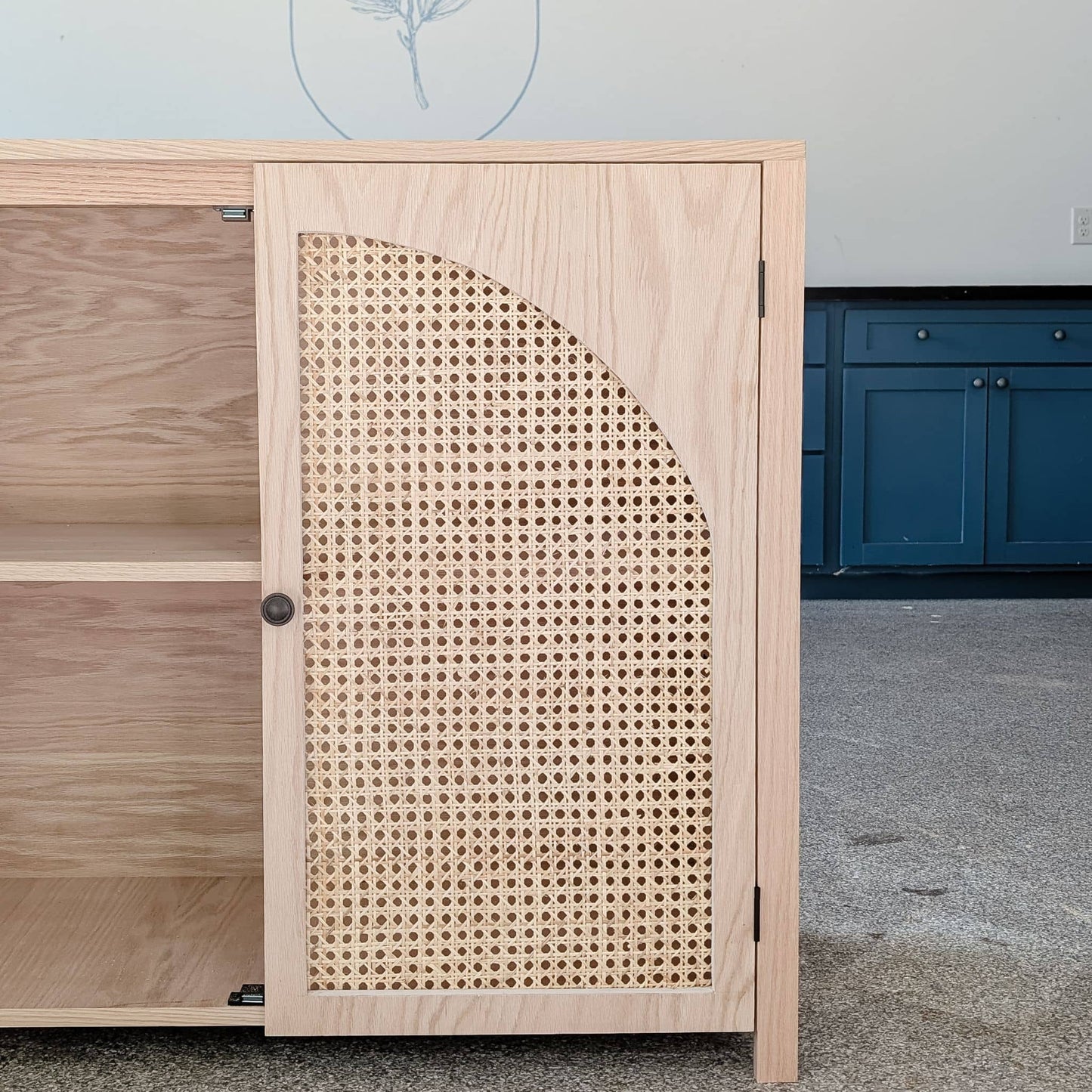 view of DIY accent cabinet with cane doors with one door closed and the other door open to reveal shelf