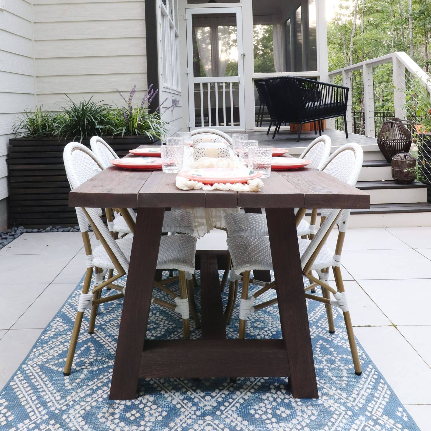 Chunky Dining Table with dark stain sitting on a blue rug with white chairs