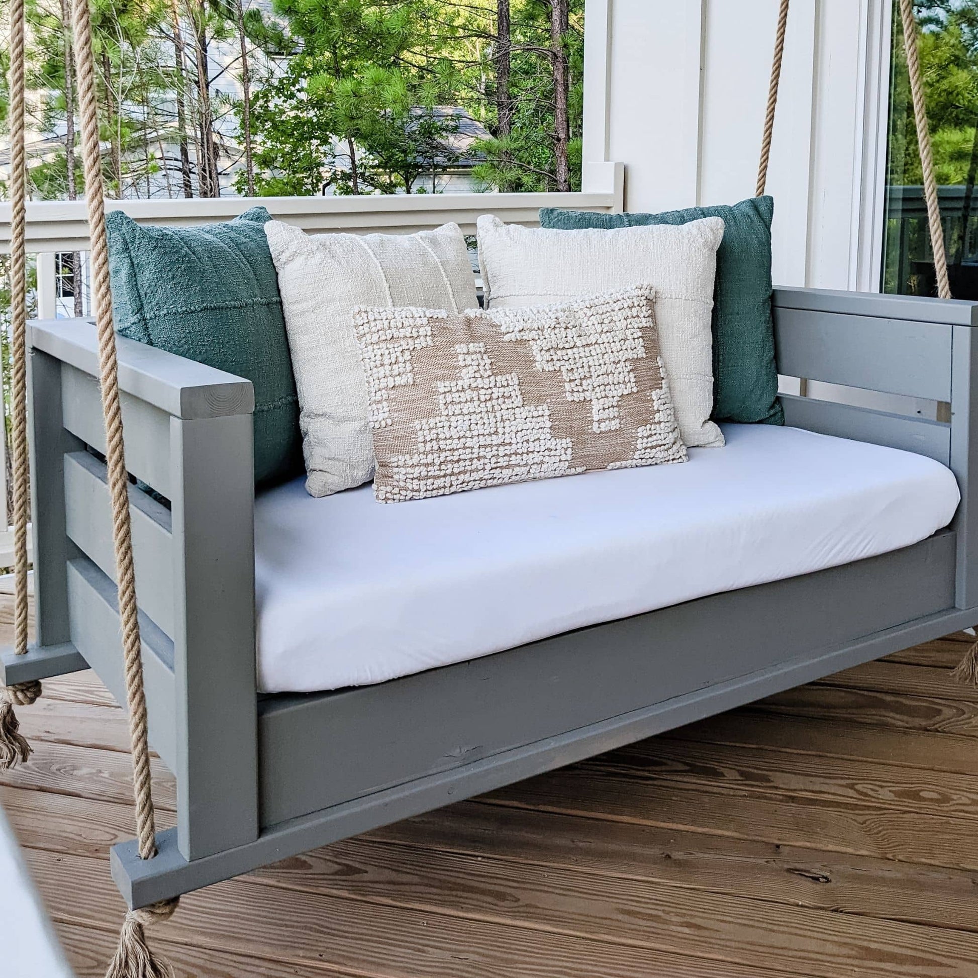 Crib Mattress Porch Swing painted light gray with green, white, and beige pillows