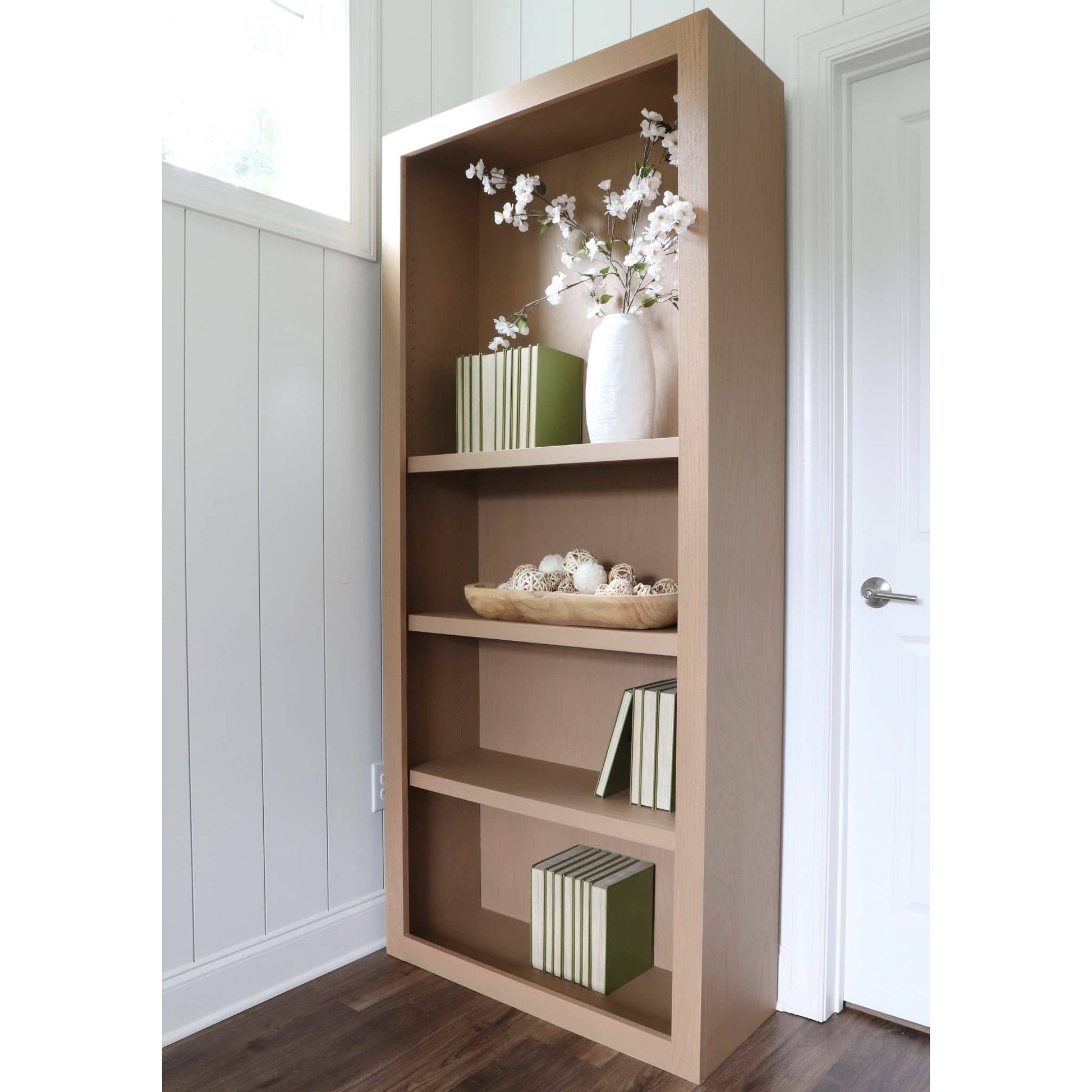 DIY plywood bookcase with decorative items against a white wall