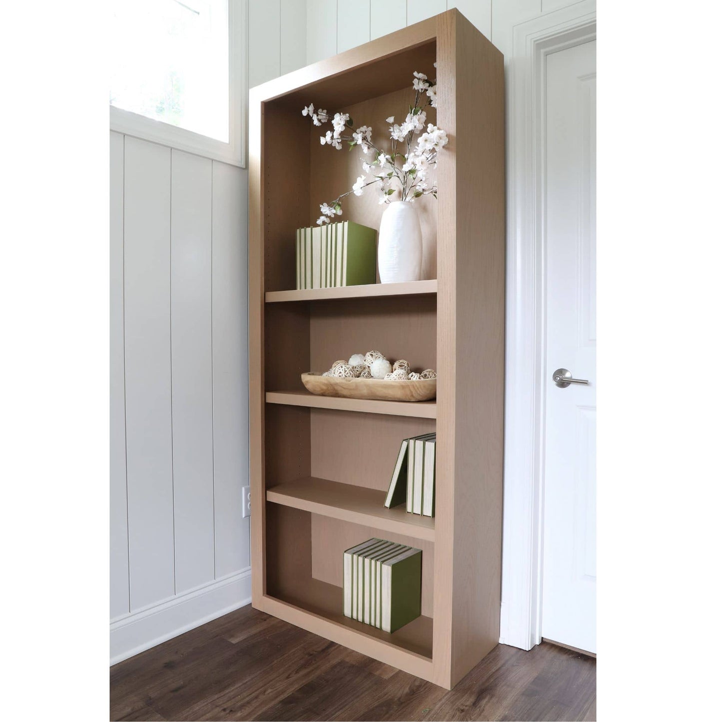 side view of DIY Wooden bookshelf with decorative items against a white wall.