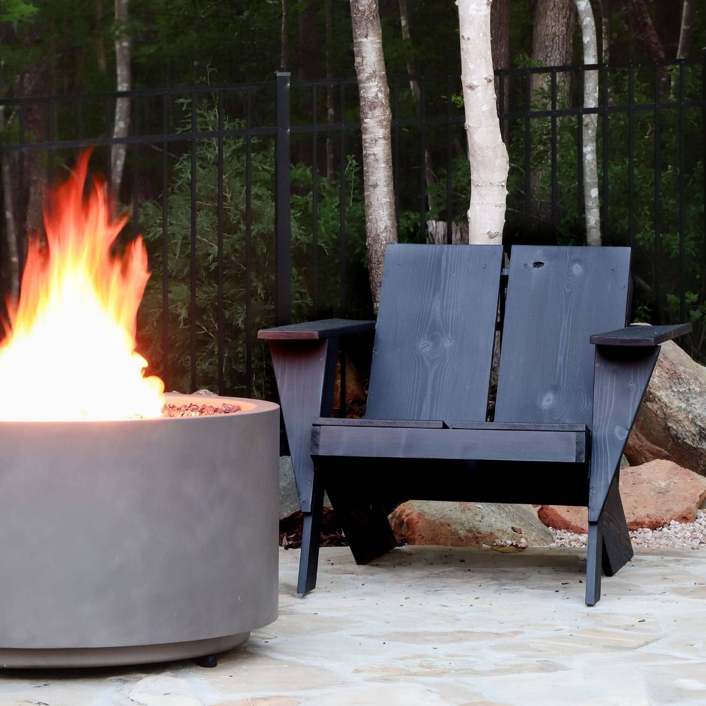 Modern Adirondack Chair stained black in front of a fire pit